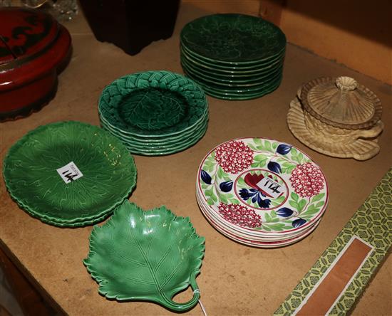 A collection of greenware plates and dishes, other pottery plates and a caneware tub, cover and stand